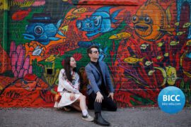 a man and a girl posing for a picture beside a wall